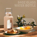 BLUEGO 84oz Water Bottle Glass with Stainless Steel Handle Large 2.5l Water Bottle with Time Markers and Silicone Sleeve Half Gallon Water Jug BPA Free for Gym Daily Use, Amber